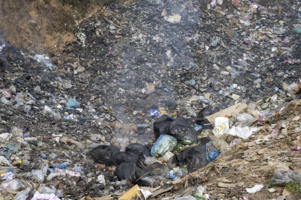 Coking rubbish dump, rubbish pit with waste and plastic rubbish, karst landscape near Vang Vieng,