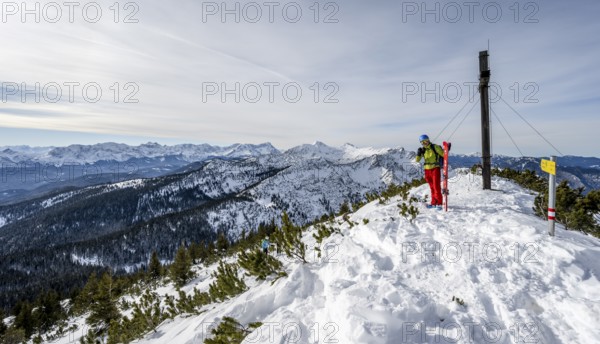 Ski tourer at the summit of the Simetsberg with summit cross, mountain panorama, Estergebirge,