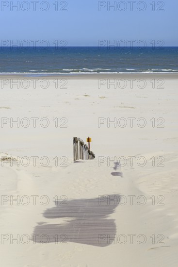 Boardwalk with sand drifts leads to the extensive sandy beach, blue sky, North Sea, Juist, East