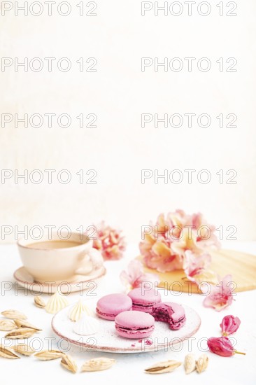 Purple macarons or macaroons cakes with cup of coffee on a white concrete background decorated with