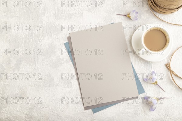 Gray paper sheet mockup with spring snowdrop crocus flowers and cup of coffee on gray concrete