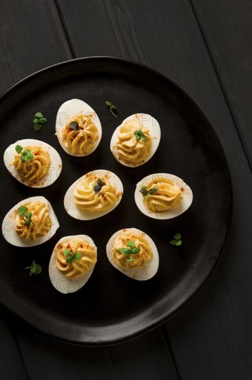 Boiled eggs stuffed with yolk with mayonnaise, on a black plate, selective focus, blurry, close-up,