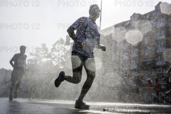 The participants of the Berlin Marathon are cooled down with a water shower in the Schöneberg