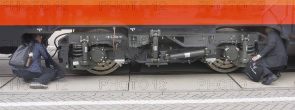 Chinese visitors to the InnoTrans trade fair in Berlin take a look at the undercarriage under a