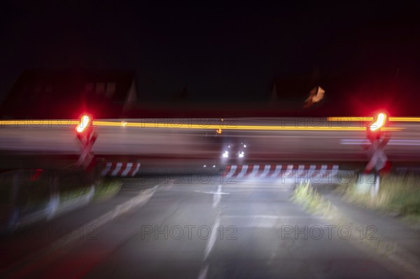 Passing train at a level crossing with barriers at night, Eckental, Middle Franconia, Bavaria,