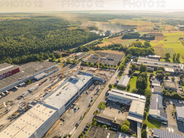 A bird's eye view of an industrial area with construction cranes and factory buildings, surrounded