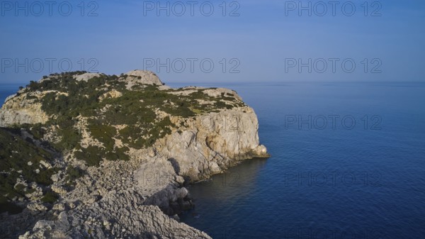 Drone shot, A rocky coastline with steep cliffs, calm sea and a clear blue sky, Anthony Quinn Bay,