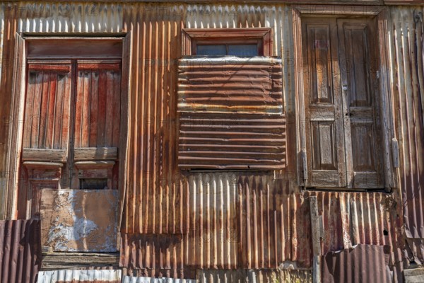 Boarded up and neglected house with a façade of rusty corrugated iron, city of Punta Arenas,