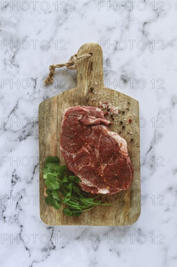 Raw pork steak, pork neck, on a chopping board, marble table, top view, with spices and coriander,