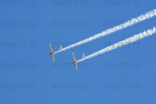Stunt aerobatic plane performing stunts in blue sky with smoke trail. Concept of teamwork,