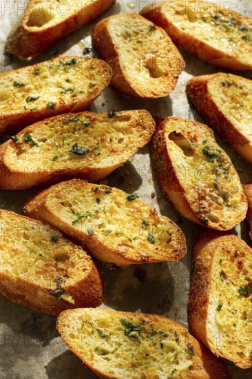 Baguette toasts, baked in the oven, with garlic butter and herbs, homemade, on a platter, top view
