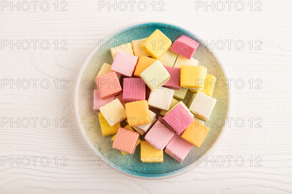 Various fruit jelly chewing candies on plate on white wooden background. apple, banana, tangerine,