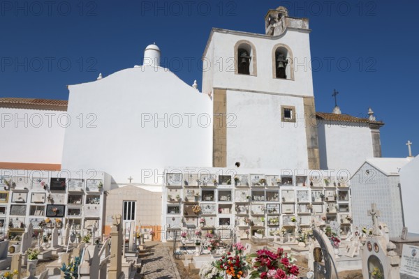 Church with cemetery in the foreground, bell tower and blue sky. Historic architecture and flower