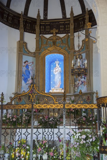 Artfully decorated church altar with flowers, statue of the Virgin Mary and golden ornaments,