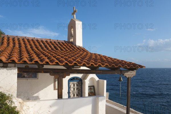 Chapel building with red bricks by the sea under a blue sky, radiates peace, Church of Agios