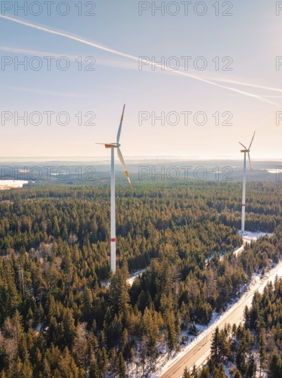 Two wind turbines protrude from a snow-covered forest, Seewald, Black Forest, Germany, Europe