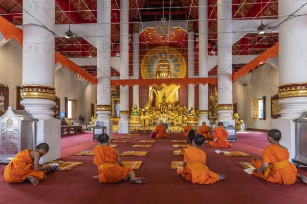 Monks and novices praying in the Buddhist temple Wat Phra Singh, Chiang Mai, Thailand, Asia