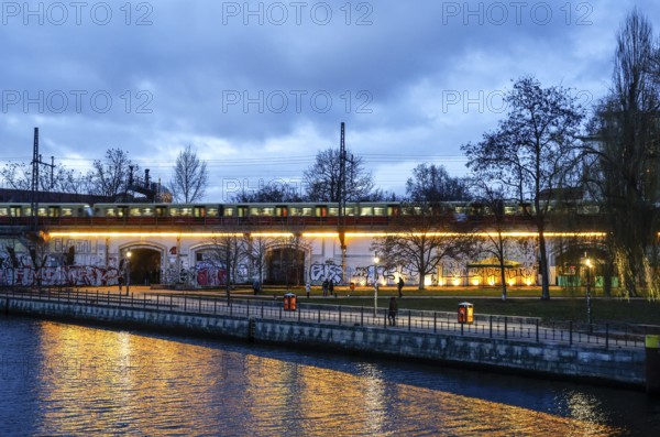S-Bahn train runs along the Spree at Monbijou Park, walkers at blue hour, Berlin, 02.01.2025