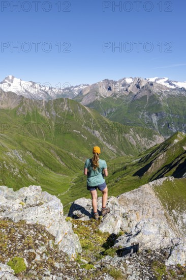 Mountaineer sitting on a rock in front of a mountain panorama with Großvenediger, mountain