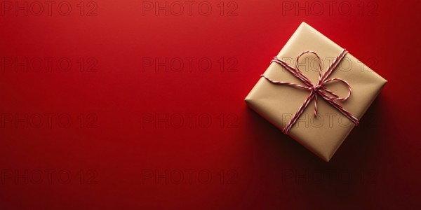 Banner with small Christmas gift box wrapped in graft paper on red background with copy space.