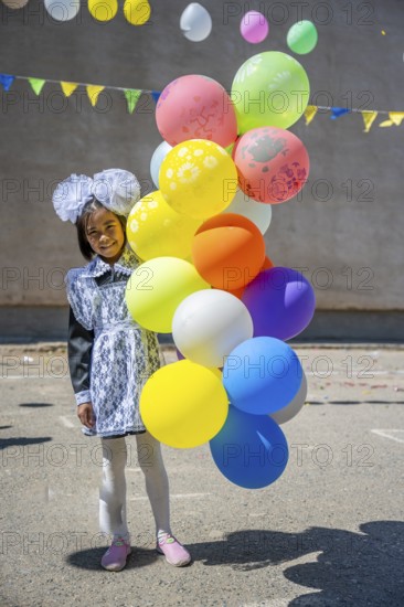 Happy schoolgirl with colourful balloons on the first day of school, Issyk-Kul region, Kyrgyzstan,