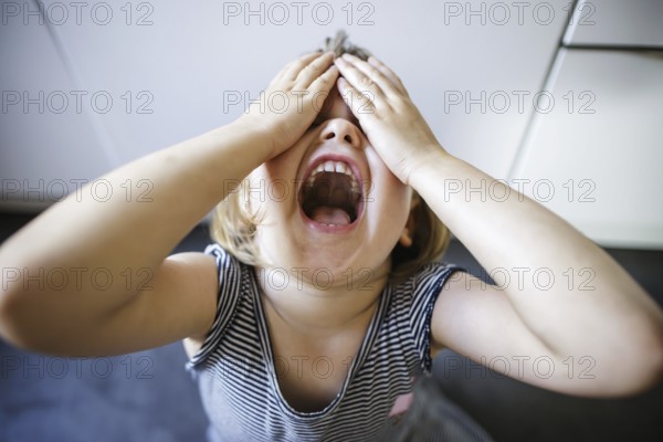 Symbolic photo on the subject of tantrums in children (staged scene) . A little girl holds her