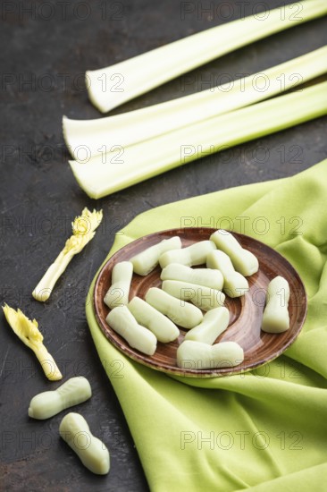 Jelly celery candies on black concrete background and green linen textile. close up, side view
