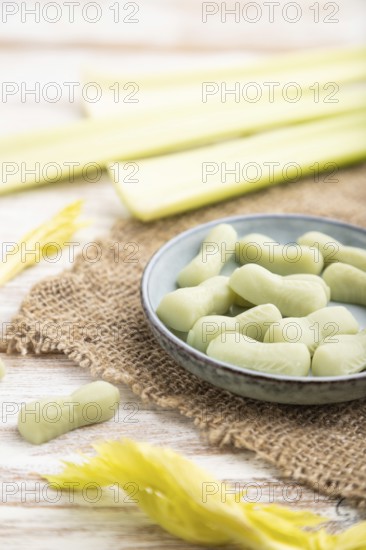 Jelly celery candies on white wooden background and linen textile. close up, side view, selective