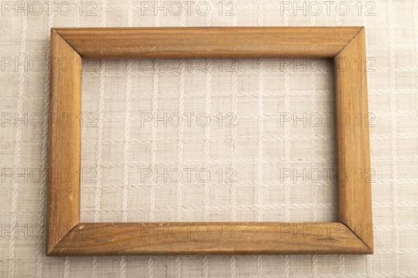 Wooden frame on smooth white linen tissue. Top view, flat lay, natural textile background and
