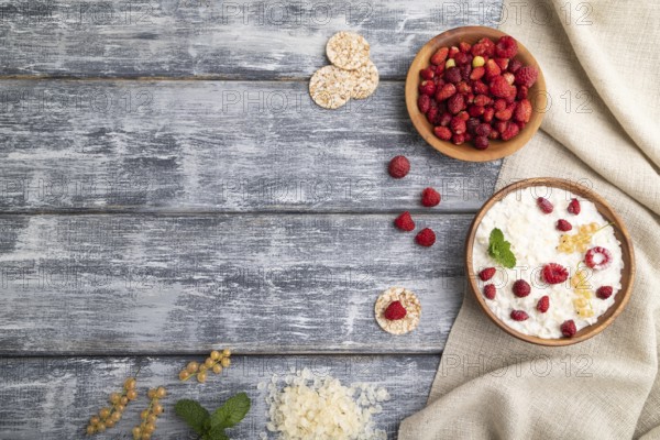Rice flakes porridge with milk and strawberry in wooden bowl on gray wooden background and linen