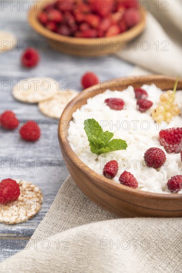 Rice flakes porridge with milk and strawberry in wooden bowl on gray wooden background and linen