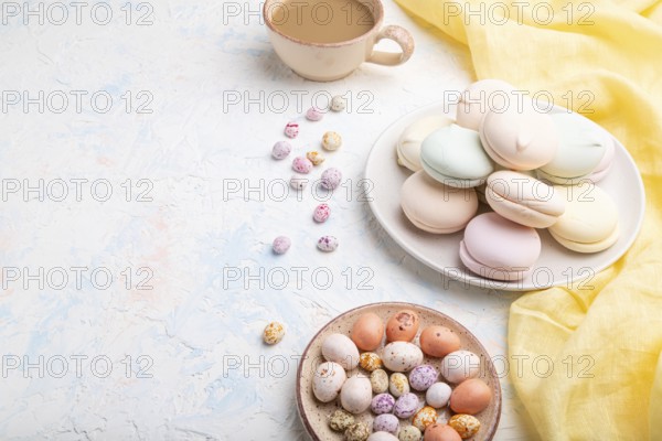 Colored zephyr or marshmallow with cup of coffee and dragees on white concrete background and