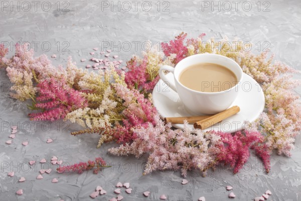 Pink and red astilbe flowers and a cup of coffee on a gray concrete background. Morninig, spring,
