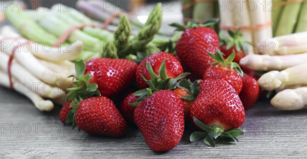 Green asparagus, white asparagus and fresh strawberries decorated on a rustic wooden table