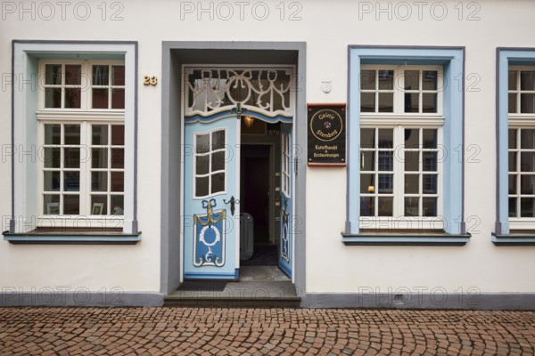 Magnificent entrance with blue, decorated entrance door to the art trade and restorations of the