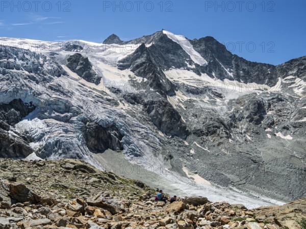 Tourists at mountain hut Cabane de Moiry, viewing at the retreating Moiry glacier, Valais,