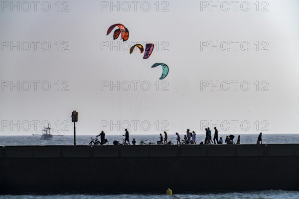 Kitesurfer off the coast of Scheveningen, walkers on the harbour pier, The Hague, Netherlands