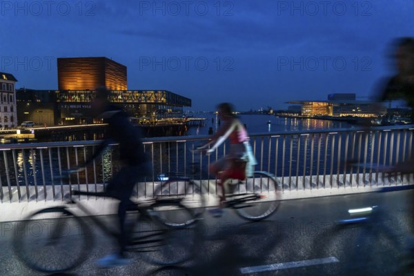 Cyclists on the Inderhavnsbroen cycle and footpath bridge, across the harbour, at night, at Nyhavn,