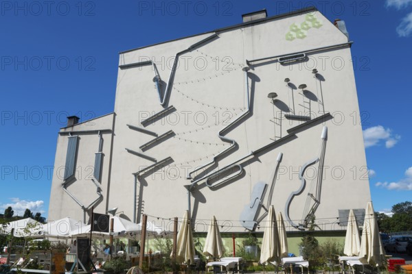 Façade of a building with large, attached instruments as an art installation, mural, Green Symphony