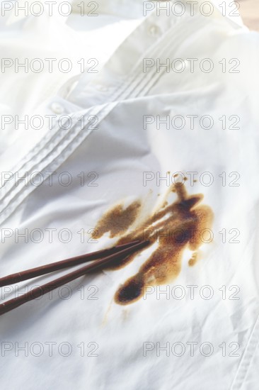 White shirt stained with soy sauce and chopsticks lying on it, no people, close-up, selective focus