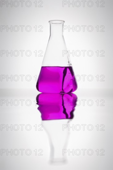 A glass bottle with purple liquid in a laboratory