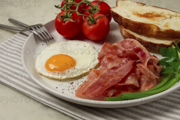 Breakfast, fried egg, bacon and bread, with cherry, on a light background, homemade, no people