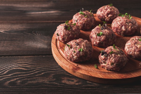 Raw meatballs, with micro greenery, on a cutting board, homemade, rustic, no people