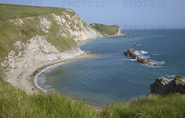A line of limestone stumps cross Man o' War bay on the Jurassic coast near Lulworth Cove, Dorset,