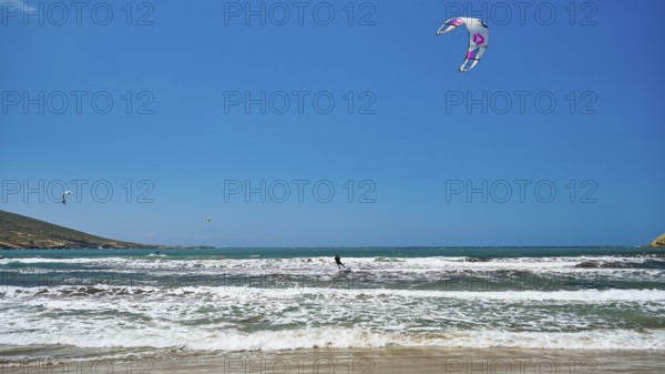 Kitesurfer on wavy sea under blue sky with kite, surfer's paradise, kitesurfer, windsurfer,