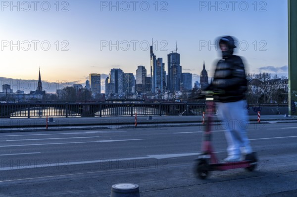 Skyline of the city centre of Frankfurt am Main, e-scooter on the raft bridge, dusk, river Main,