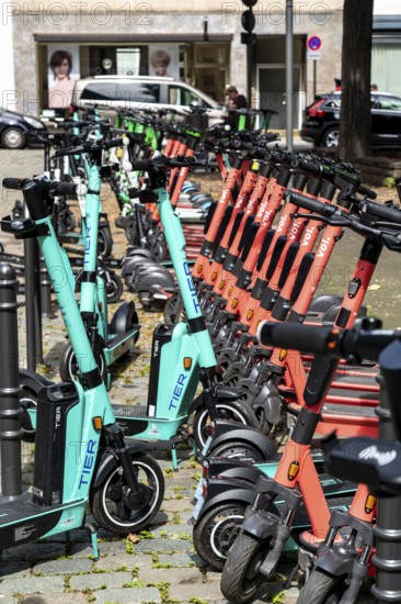 Electric scooters, e-scooters are parked in large numbers on the Burgmauer road, in front of
