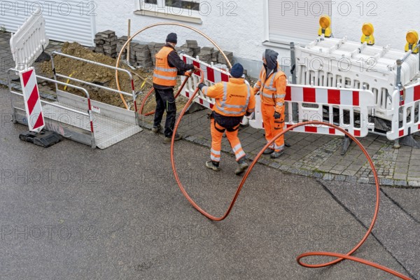 Construction workers laying fibre optic cable, cable trench, construction site, fibre optic