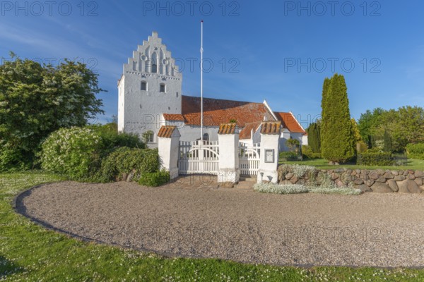 Whitewashed church in Dalby, side view, red roof, cemetery, stepped gable, entrance gate, stone