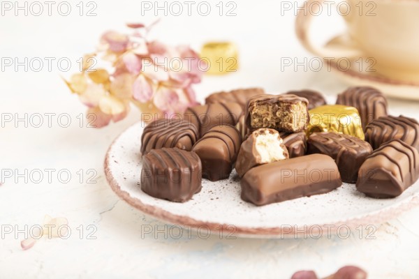 Chocolate candies with cup of coffee and hydrangea flowers on a white concrete background. side